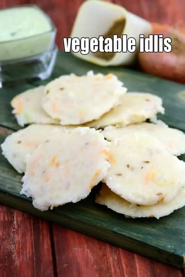 Soft steamed vegetable idlis served on a banana leaf, showing grated vegetables inside the idlis, with coconut chutney and vegetables in the background.