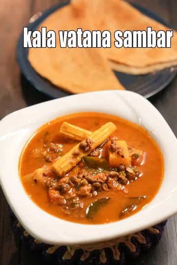 An image showcasing a hearty and colorful bowl of Kala Vatana Sambar, a protein-rich South Indian stew made with dried black peas. The dish is served in a dark ceramic bowl and features a flavorful, dark-orange broth filled with tender black peas, chunky cubes of red pumpkin (kaddu), bottle gourd (doodhi), and pieces of drumsticks. The sambar is garnished with fresh green cilantro leaves. In the background, a small white bowl contains some of the raw dried black peas, set against a dark, rustic wooden surface.