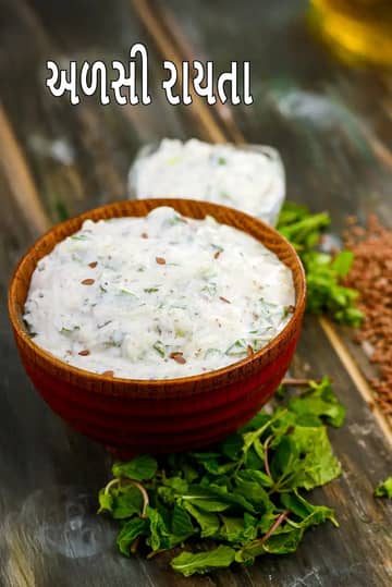 લાકડાના એક બાઉલમાં ક્રીમી અળસીનું રાયતું છે, જેને શેકેલી અળસી અને સમારેલી કોથમીરથી સજાવવામાં આવ્યું છે. આ બાઉલ લાકડાના ટેબલ પર રાખેલું છે, જેની આસપાસ ફુદીનાના તાજા પાન અને પાછળ અળસીના દાણાનો ઢગલો જોવા મળે છે.