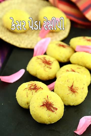 કેસરની સુગંધવાળા પીળા રંગના કેસર પેડા, ઉપર કેસરના તાંતણાથી સજાવેલા, કાળા સર્વિંગ સ્લેબ પર ગોઠવાયેલા છે, આસપાસ ગુલાબની પાંખડીઓ અને પાછળ ઉત્સવી કાપડ દેખાય છે.