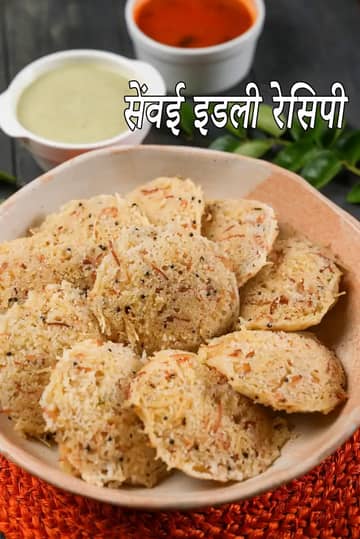 एक कटोरे में रखी हुई वर्मिसेली इडली, जो भुनी हुई सेमिया से बनी है और राई व मसालों से सजी हुई है, साथ में पीछे नारियल की चटनी और लाल चटनी परोसी गई है।