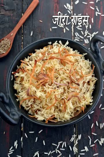 तली हुई प्याज से सजा हुआ खिला-खिला जीरा राइस, एक काली हांडी में परोसा गया।