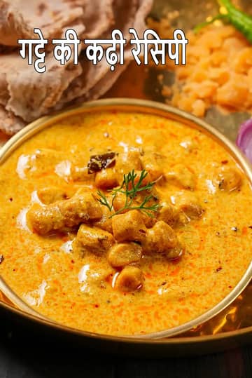 पीतल के बर्तन में परोसी गई पारंपरिक राजस्थानी गट्टे की कढ़ी, जिसमें बेसन के गट्टे मलाईदार पीली दही की कढ़ी में डूबे हुए हैं, ऊपर हरी सजावट है और साथ में रोटी, हरी मिर्च, प्याज़ व अन्य सामग्री रखी हुई है।