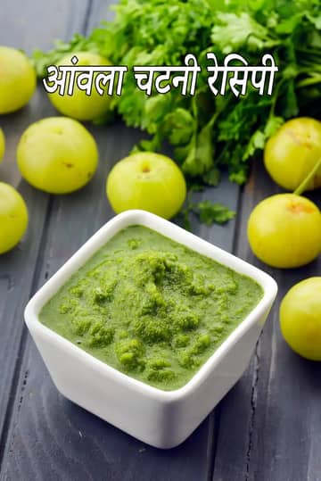 एक छोटे वर्गाकार सफेद कटोरे में ताजी हरी आंवला चटनी, जिसके चारों ओर साबुत आंवले और हरी धनिया की पत्तियां सजी हुई हैं।