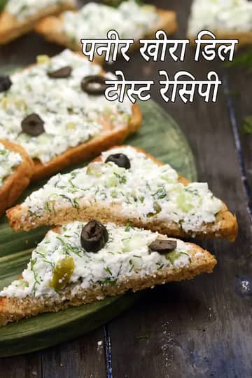 हरे प्लेट पर रखे टोस्टेड ब्रेड स्लाइस, जिन पर क्रीमी पनीर, खीरा और सोआ (डिल) का मिश्रण लगा है और ऊपर से काले ऑलिव्स से गार्निश किया गया है। बैकग्राउंड डार्क वुडन है और इमेज पर “Paneer Cucumber Dill Toast” लिखा है।