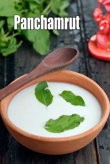 Traditional Panchamrut served in a clay bowl with Tulsi leaves, alongside a wooden spoon.