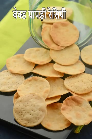 प्लेट में रखी हुई बेक्ड पापड़ी, हल्के सुनहरे रंग की गोल और कुरकुरी पापड़ी बिस्किट, जो एक हेल्दी भारतीय बेक्ड स्नैक के रूप में तैयार की गई है।