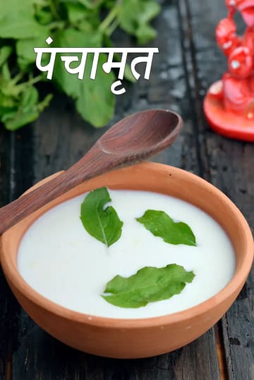 मिट्टी के कटोरे में परोसा गया पारंपरिक पंचामृत, जिसमें तुलसी के पत्ते और एक लकड़ी का चम्मच है।