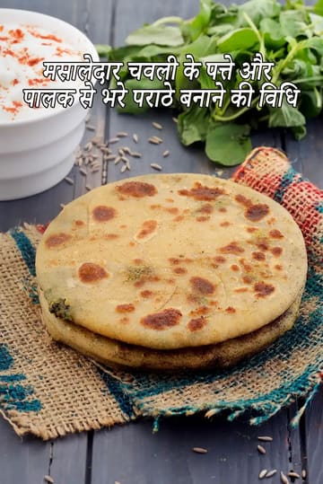 देसी कपड़े पर रखी हुई चवली के पत्ते और पालक से भरी मसालेदार पराठों की एक परत दिखाई दे रही है। पीछे लाल मिर्च पाउडर से सजी सफेद दही की कटोरी, ताजी हरी पत्तेदार सब्जियाँ और जीरा लकड़ी की सतह पर रखे हैं।