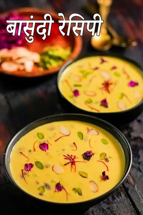 काले बर्तनों में परोसी गई गुजराती बासुंदी, जो केसर से बनी गाढ़ी दूध की मिठाई है, ऊपर से बादाम, पिस्ता, गुलाब की पंखुड़ियाँ और केसर से सजाई गई है, डार्क रस्टिक सतह पर रखी हुई।