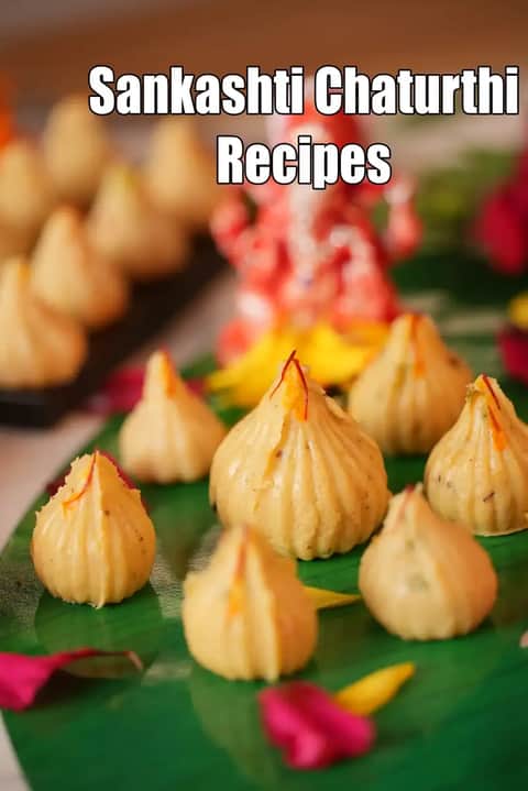 Steamed modaks arranged on a banana leaf for Sankashti Chaturthi, garnished with saffron strands, with a Lord Ganesha idol blurred in the background and the text “Sankashti Chaturthi Recipes” displayed on the image.