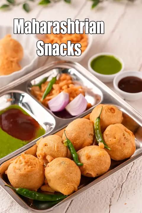 Maharashtrian snacks served in a steel plate with crispy batata vada, green chilies, chopped onions, farsan, and green & red chutney.