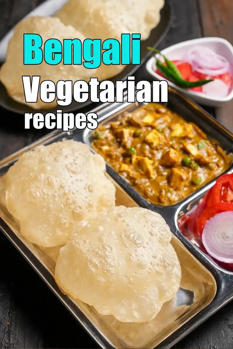 Bengali vegetarian meal served in a stainless steel thali with puffed luchi, paneer curry, sliced onions, tomatoes, and green chilli on a wooden table.