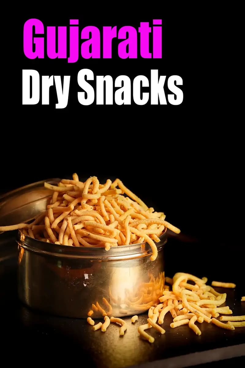Gujarati dry snacks featuring crispy sev stored in a steel container, with some sev spilled beside it on a dark background, and the text “Gujarati Dry Snacks” displayed on the image.