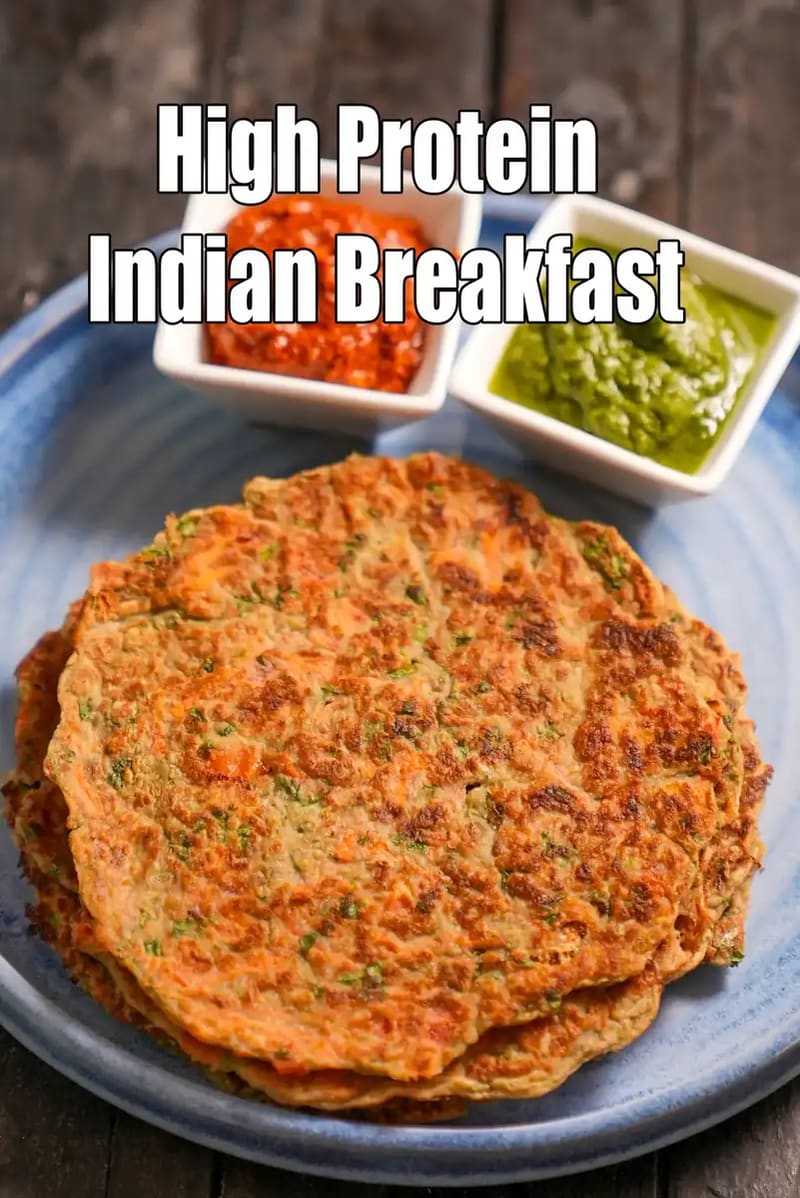 A top-down view of a stack of savory Indian pancakes (Chilla) served with green and red chutneys on a blue plate, with the text High Protein Indian Breakfast overlaid.