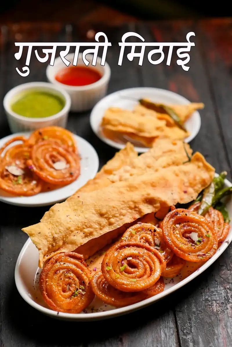 नट्स से सजी जलेबी के साथ परोसी गई गुजराती स्वीट मिठाई की थाली, साथ में समोसे और छोटी कटोरियों में चटनी, और तस्वीर पर “Gujarati Sweet Mithai” लिखा हुआ दिखाई देता है।