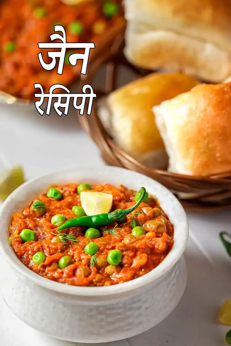 हरी मटर, हरी मिर्च और नींबू से सजी जैन पाव भाजी कटोरे में परोसी गई है, साथ में मक्खन लगे पाव रखे हैं।