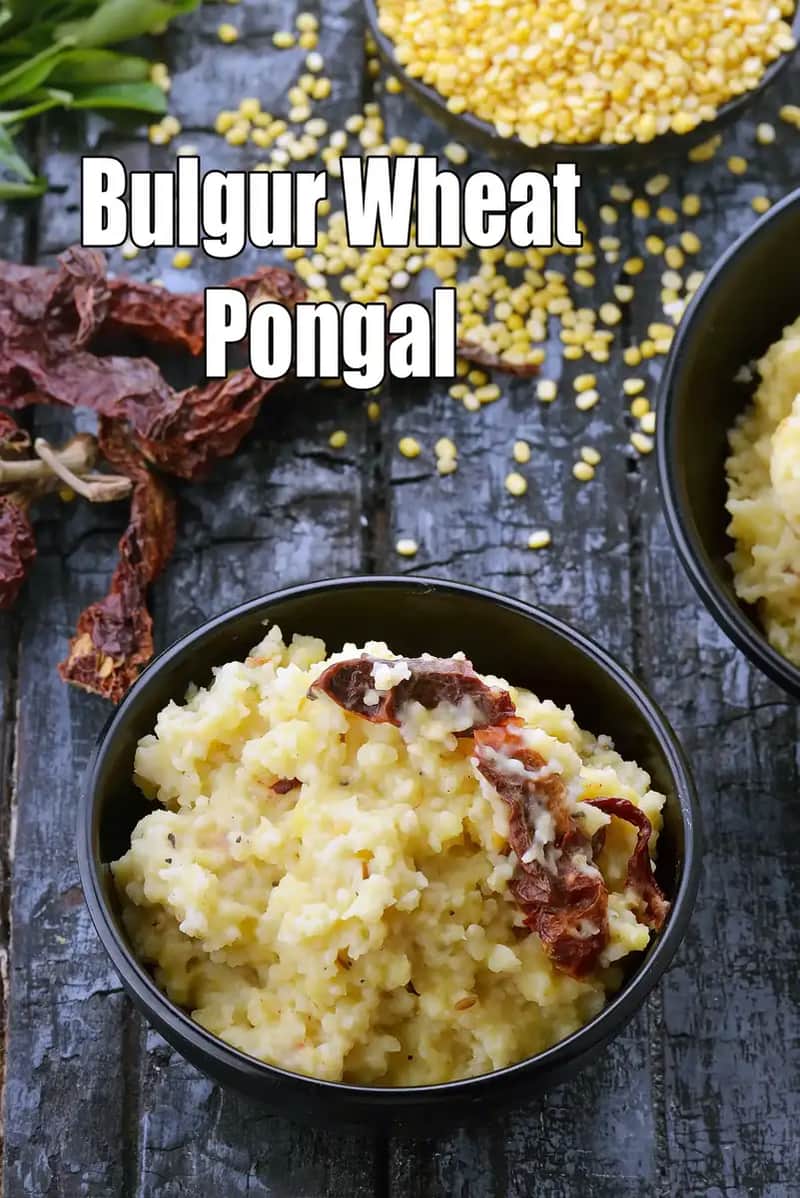 A top-view image of Bulgur Wheat Pongal served in black bowls on a rustic wooden surface. The creamy, soft pongal is garnished with fried dried red chillies. Raw bulgur wheat grains and whole dried red chillies are placed beside the bowls, highlighting the ingredients used in the dish.
